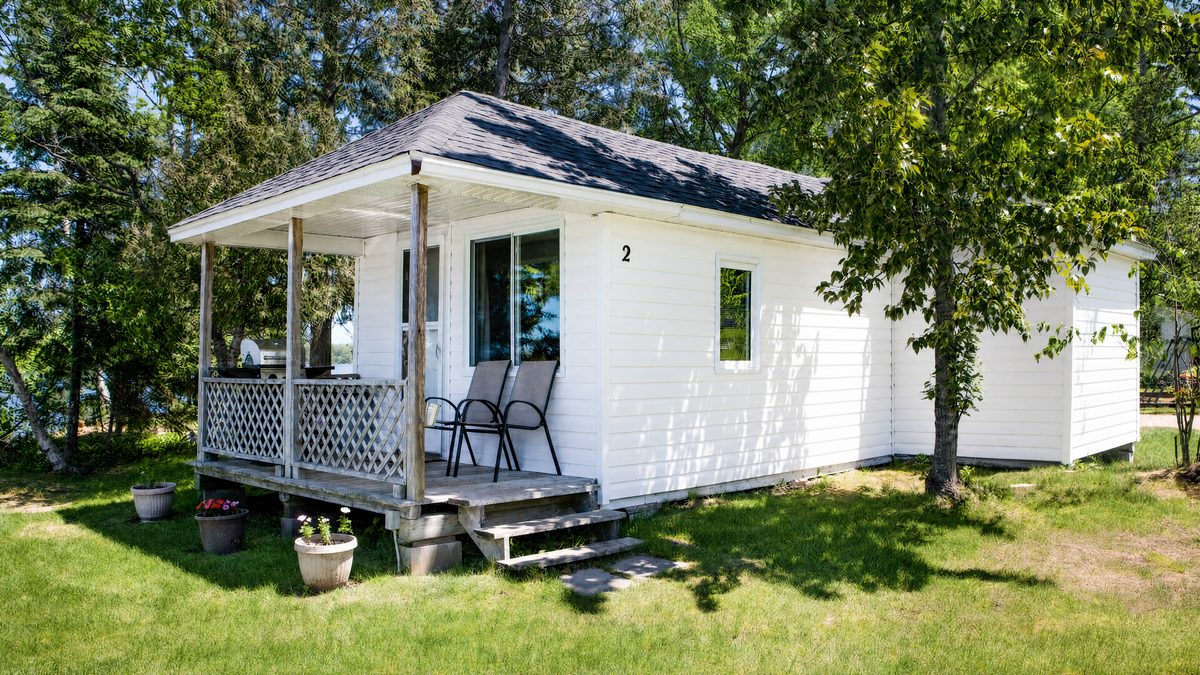Lucky Duck, a white cottage with a covered porch among the trees