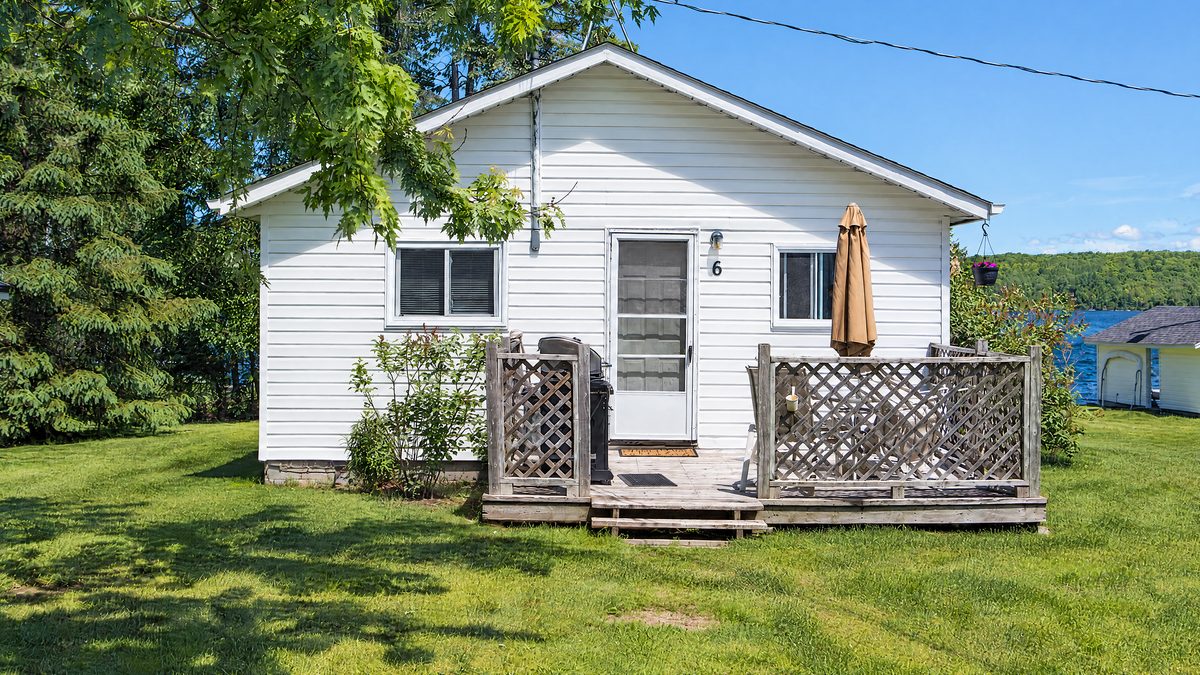 Lake Breeze, a white cottage with a deck and a patio umbrella