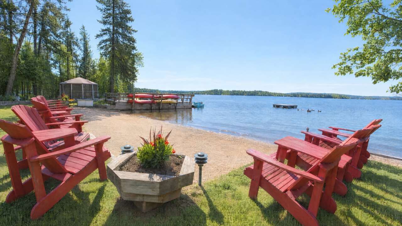 Red Adirondack chairs around a planter on the lawn and beach at Cozy Camp, looking out over Lake Nosbonsing